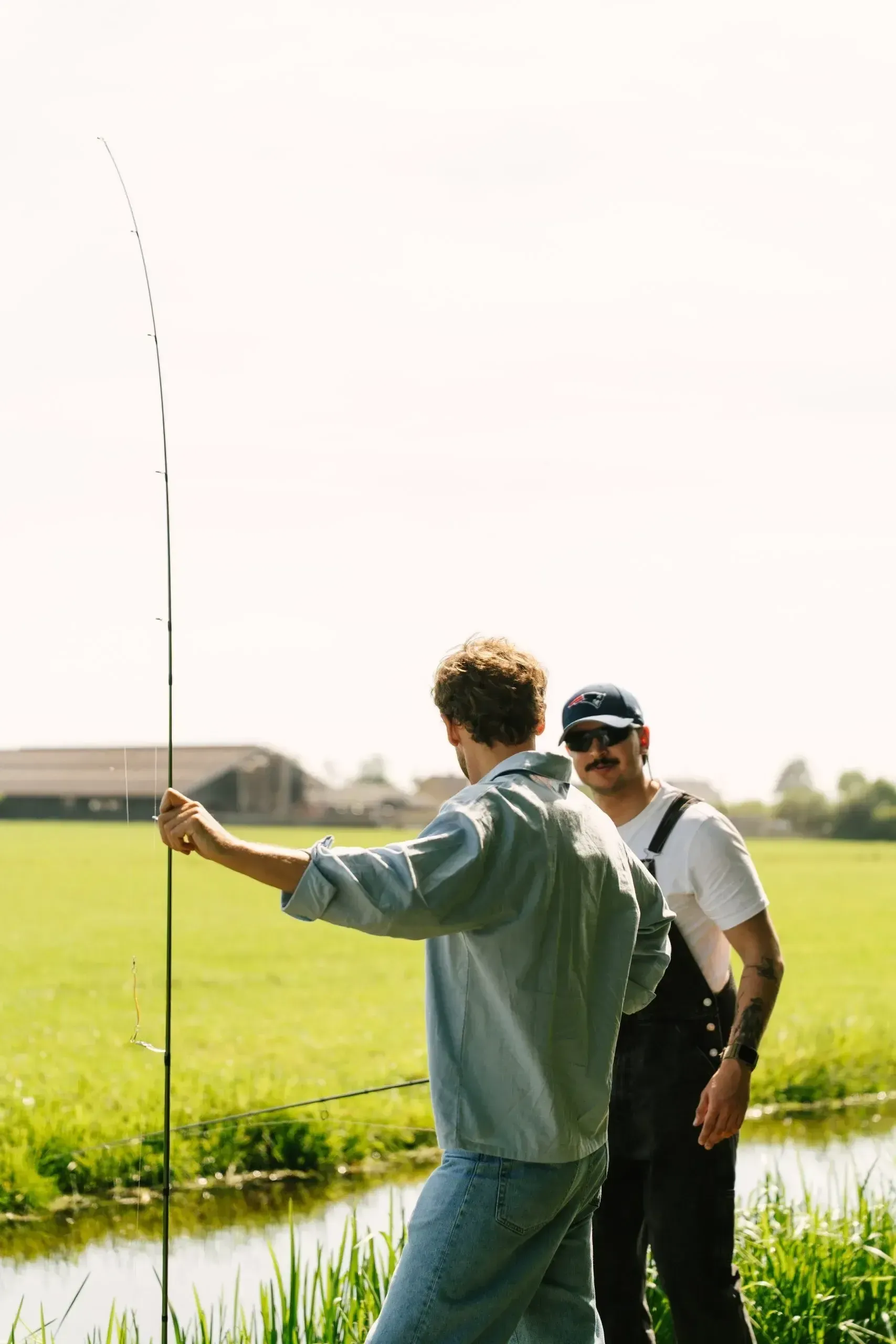 Two people fishing together at the edge of a canal