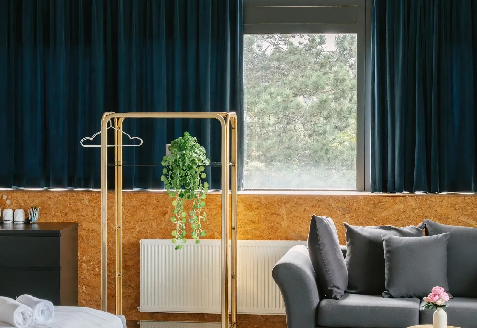 A room with green curtains, a brass rail and a sofa by the window